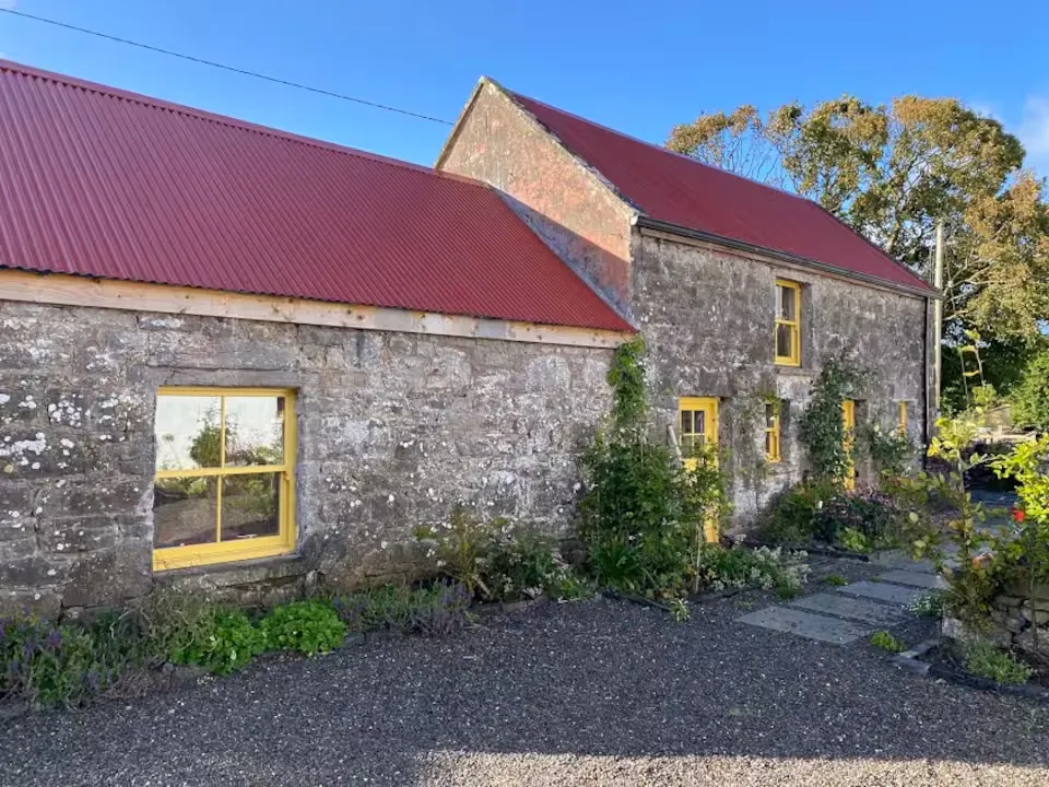 The Stables at Houndswood Farm, a converted stone outbuilding with a red roof and yellow door