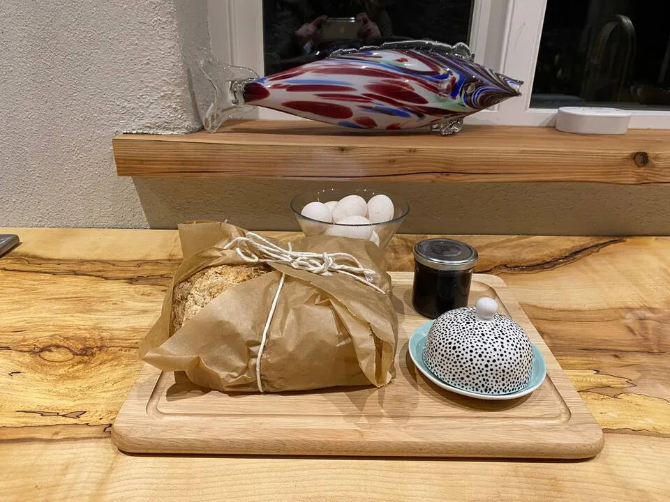 Welcome tray on the kitchen counter: wrapped sourdough, fresh eggs, jam and a handmade butter dish