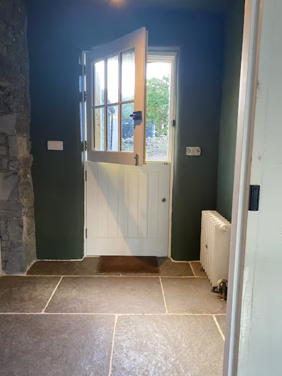 The entrance hallway — Irish split door open to the yard, flagstone floor, dark green walls
