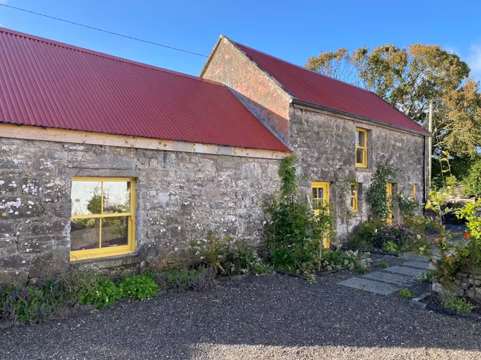 Houndswood farmhouse — stone walls, red tin roof, mustard yellow windows
