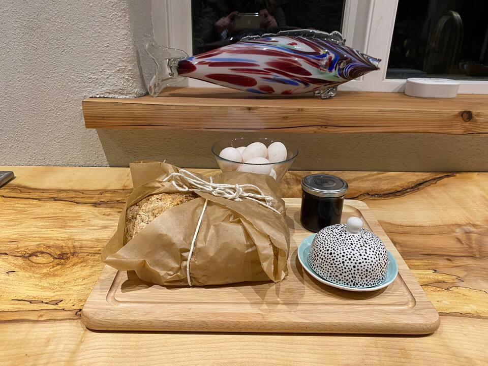 Welcome tray on the kitchen counter — wrapped sourdough, fresh eggs, jam and a handmade butter dish