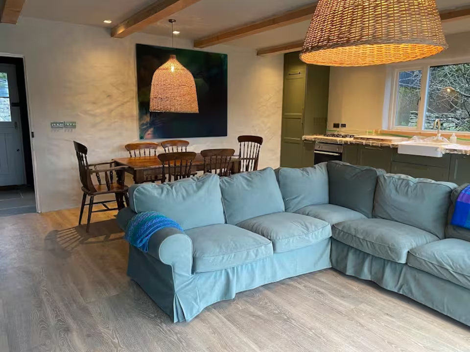 Teal sofa in the living area with the kitchen and dining space visible beyond